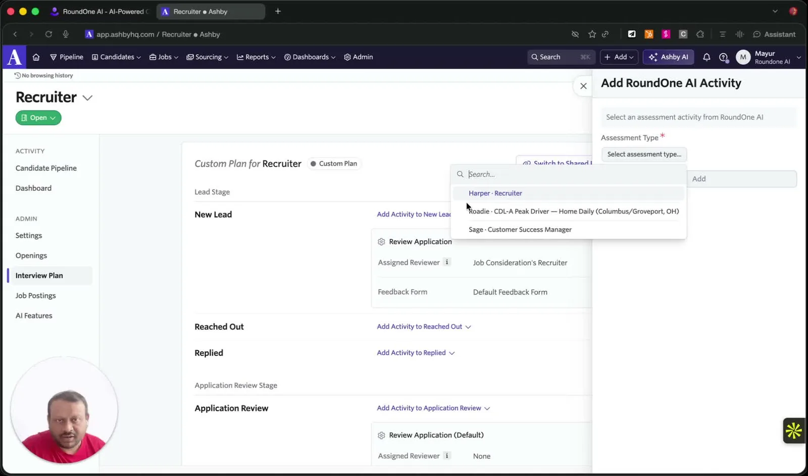The Add RoundOne AI Activity panel in Ashby with the Assessment Type dropdown open, listing agents such as "Harper · Recruiter" and "Sage · Customer Success Manager"
